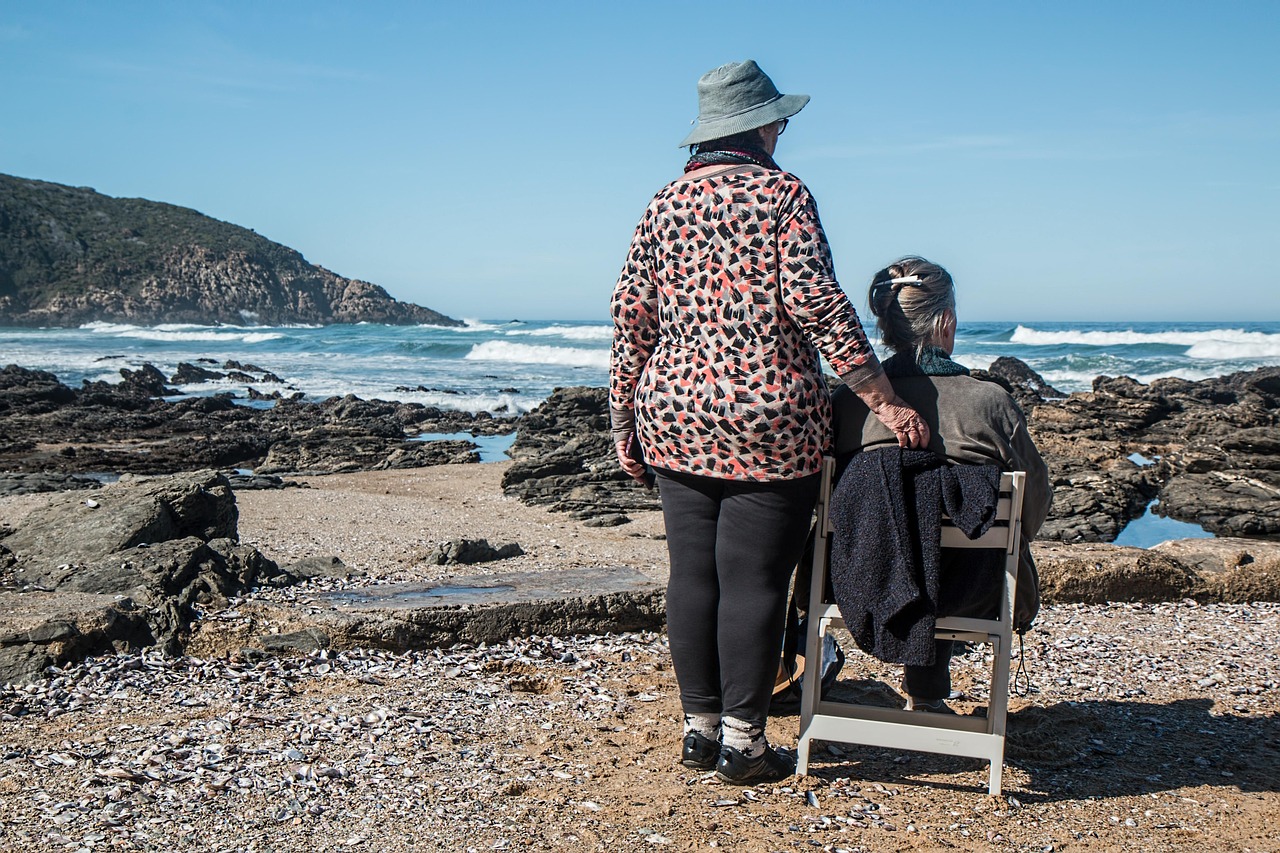 Senior assisted living resident spending time outdoors with a caregiver near the ocean